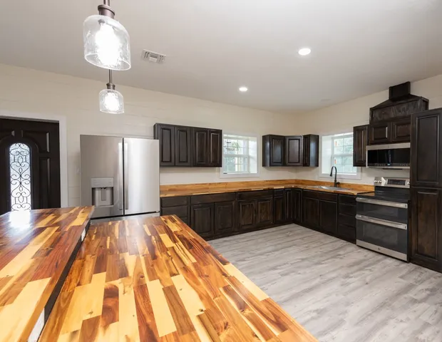 a open kitchen with a refrigerator a stove top oven a counter space and wooden floor