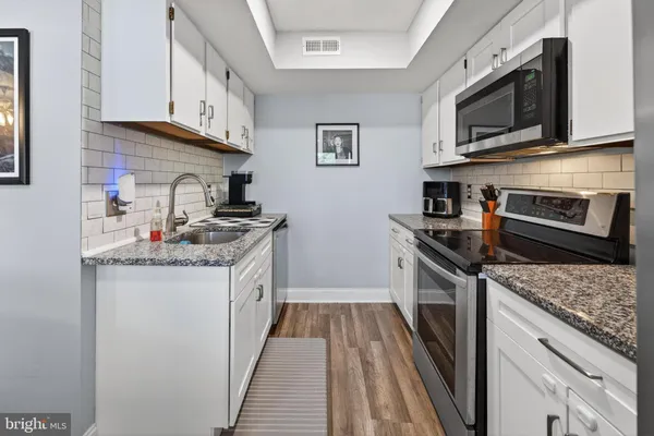 a kitchen with stainless steel appliances granite countertop a sink stove microwave and refrigerator
