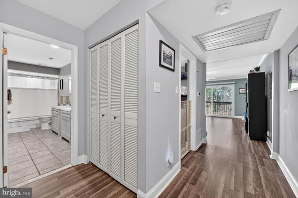 a view of a hallway with wooden floor and a bathroom