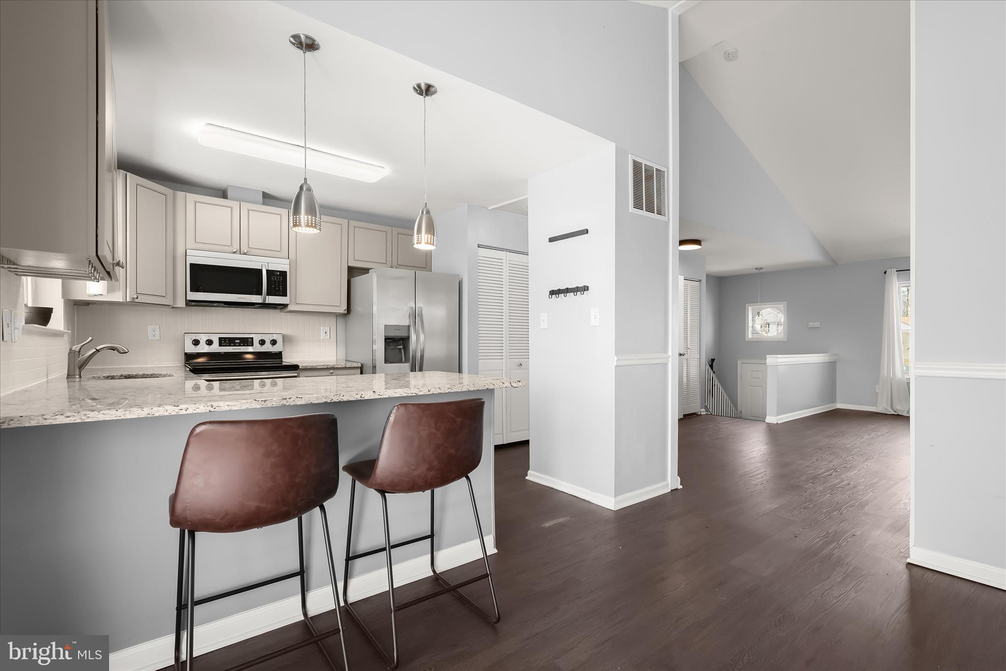 8624 Castlemill Circle Nottingham, MD 21236 - Photo 13 of 34 a kitchen with stainless steel appliances granite countertop a stove a sink a microwave a refrigerator a dining table and chairs with wooden floor