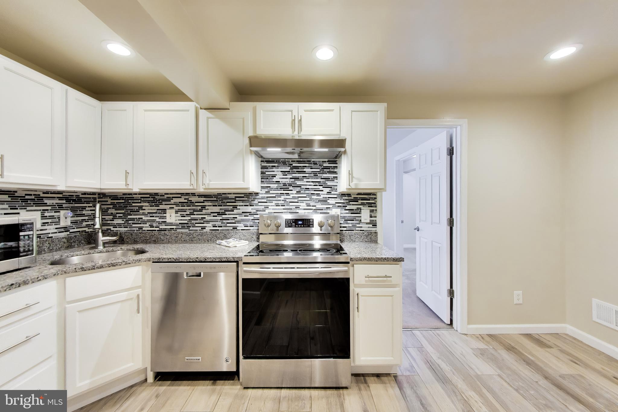 9200 Linden Grove Court Silver Spring, MD 20910 - Photo 44 of 72 a kitchen with stainless steel appliances granite countertop a stove and white cabinets