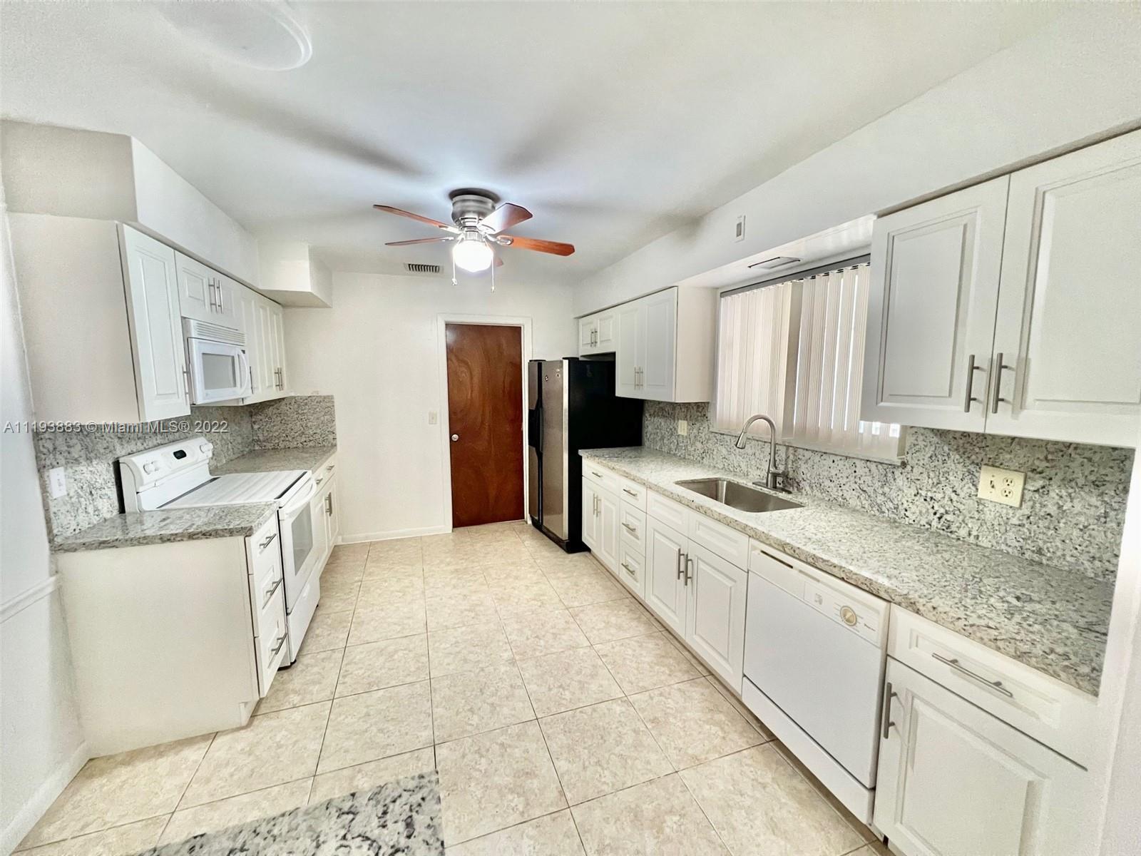 4407 Arthur Street Hollywood, FL 33021 - Photo 3 of 25 a kitchen with stainless steel appliances granite countertop a sink a stove a refrigerator cabinets and living room view