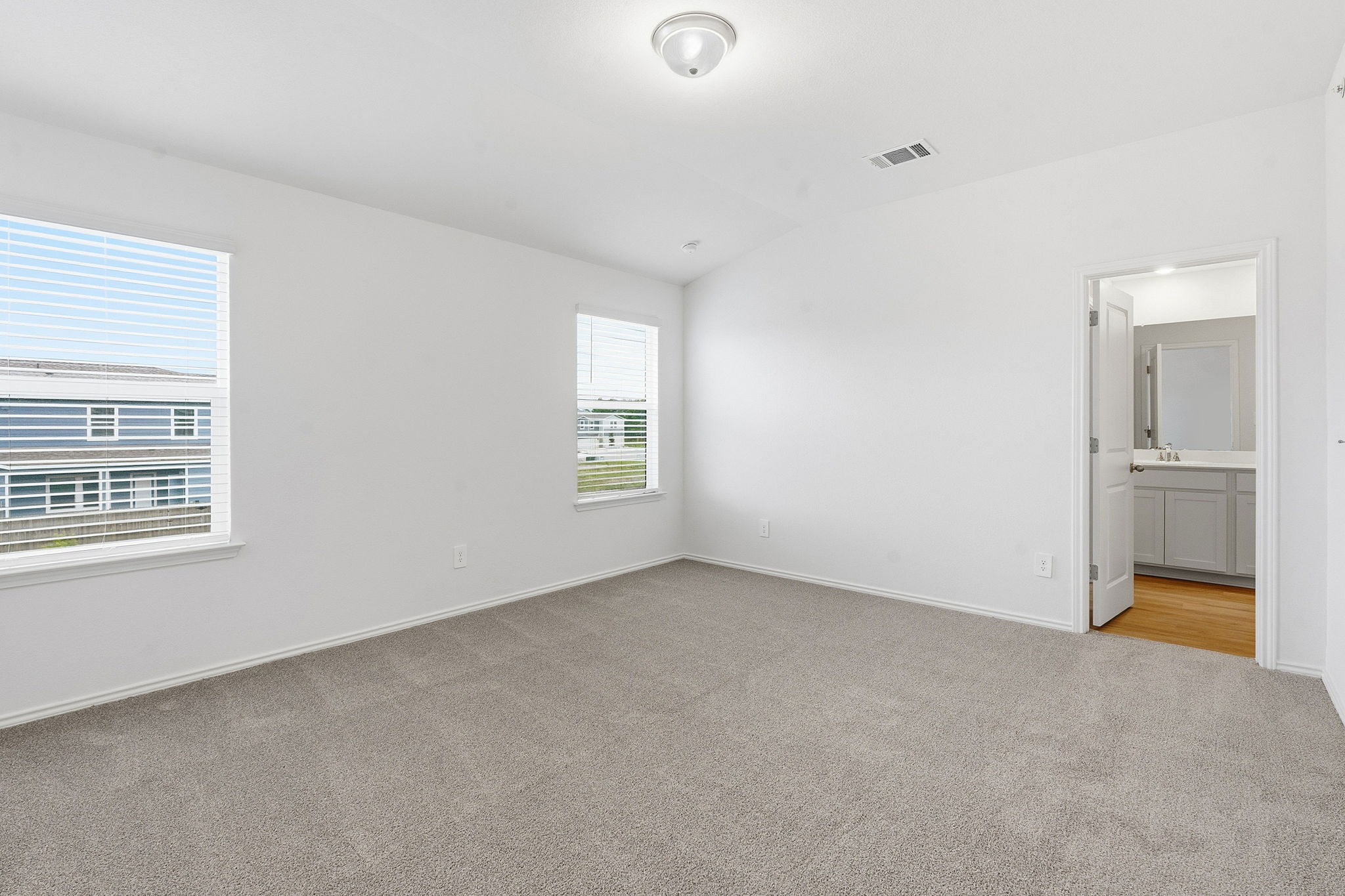 164 Cinnabar Lane, Unit 2 Kyle, TX 78640 - Photo 10 of 21 Carpeted room with white walls, two windows featuring horizontal blinds, and a flush mount ceiling light