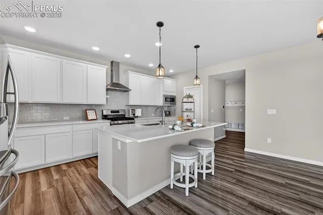 a kitchen with stove a sink and white cabinets with wooden floor