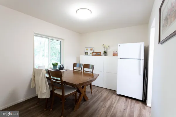 a view of a dining room with furniture a refrigerator and wooden floor