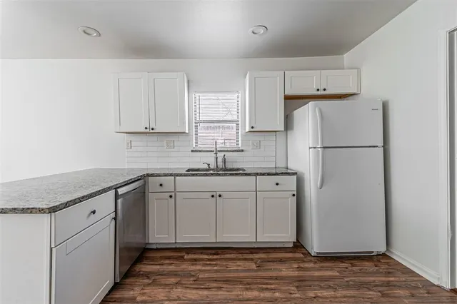 a kitchen with stainless steel appliances granite countertop a refrigerator sink and white cabinets