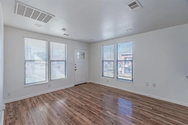 an empty room with wooden floor and windows