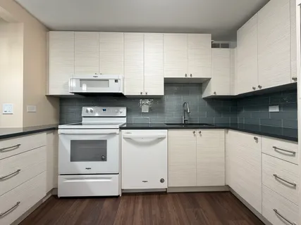 a kitchen with granite countertop white cabinets and white appliances