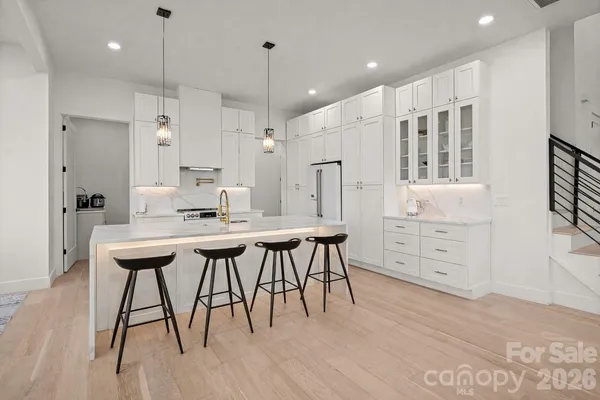 a kitchen with stainless steel appliances kitchen island a table chairs in it and wooden floors