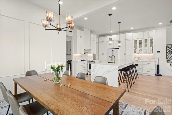 a view of a dining room and livingroom with furniture wooden floor a chandelier