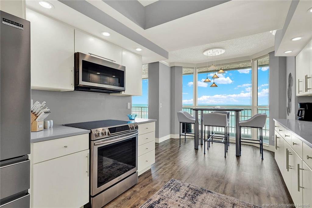8600 South Ocean Drive, Unit LN3 Jensen Beach, FL 34957 - Photo 20 of 63 a kitchen with stainless steel appliances granite countertop a stove top oven a sink dishwasher a dining table and chairs with wooden floor