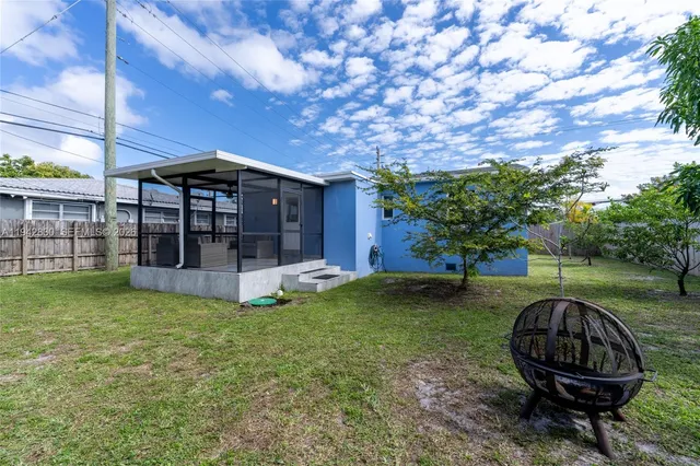 a view of a backyard with table and chairs potted plants and large tree