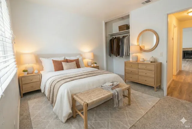 a bedroom with a bed a mirror on dresser and a chandelier