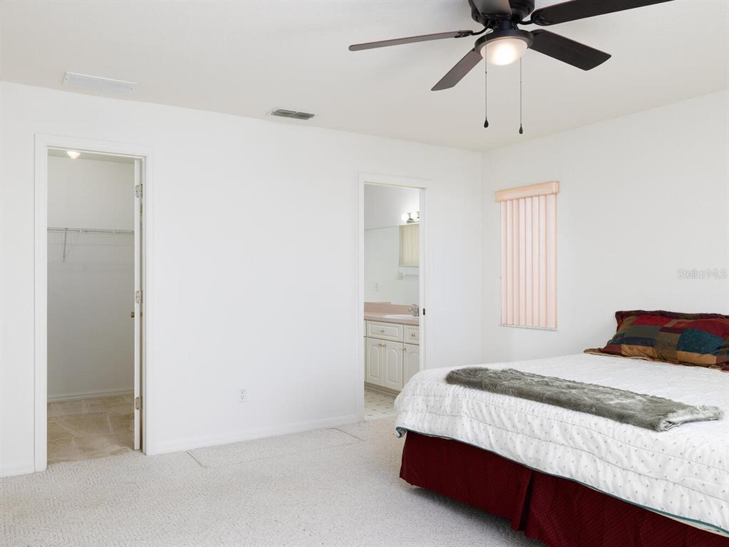 6086 Southwest 98th Loop Ocala, FL 34476 - Photo 12 of 49 a bedroom with a bed and a chandelier fan
