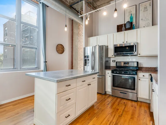 a kitchen with stainless steel appliances granite countertop a refrigerator a stove and a sink