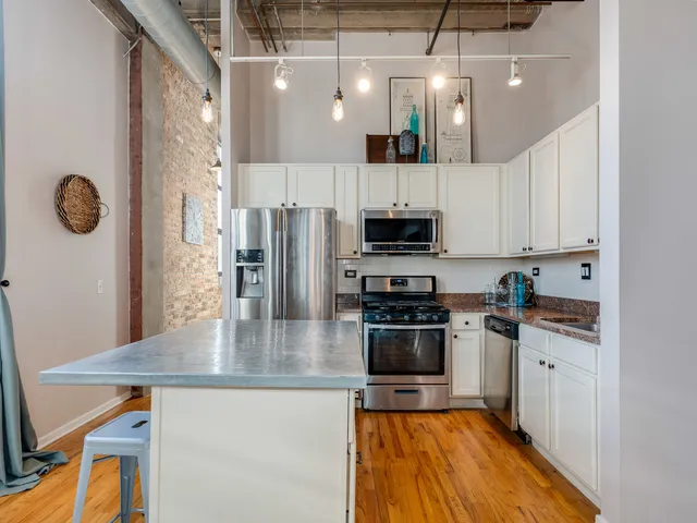 a kitchen with stainless steel appliances granite countertop a sink a stove top oven a counter space and cabinets