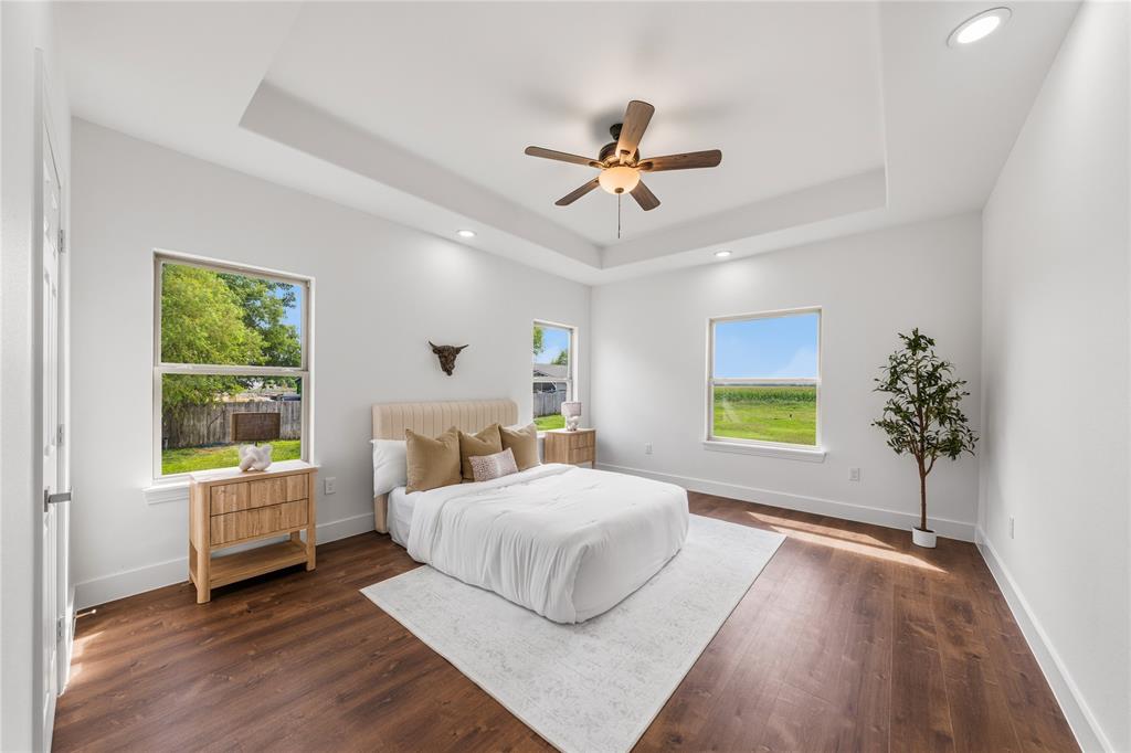 1128 Newton Road Ferris, TX 75125 - Photo 15 of 28 Spacious bedroom featuring a tray ceiling with recessed lighting, wood-finish flooring, and multiple windows
