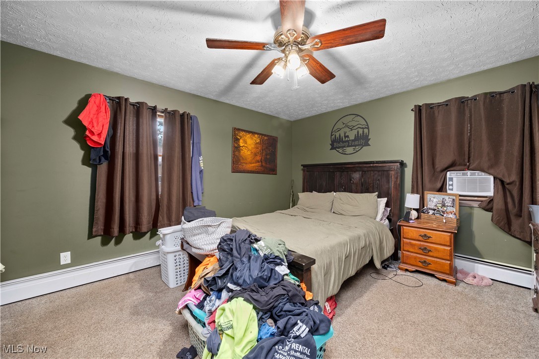 8802 West Mason Road Castalia, OH 44824 - Photo 21 of 49 Carpeted bedroom with a textured ceiling, a baseboard radiator, ceiling fan, and cooling unit