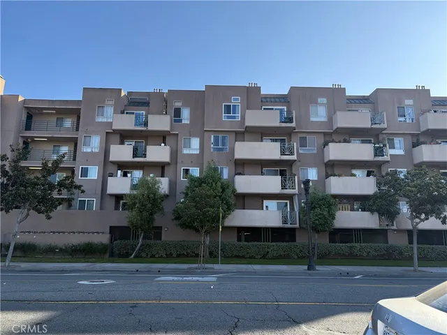 a front view of a residential apartment building with a yard and plants