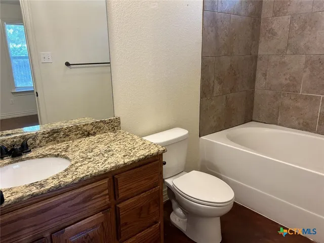 a bathroom with a granite countertop toilet sink and mirror