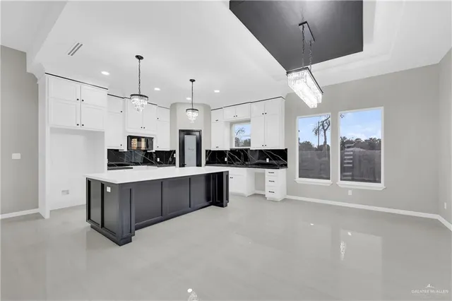 a large white kitchen with stainless steel appliances kitchen island granite countertop a stove a sink a refrigerator and white cabinets with wooden floor