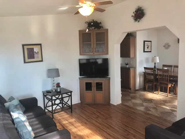 a living room with furniture a flat screen tv and kitchen view