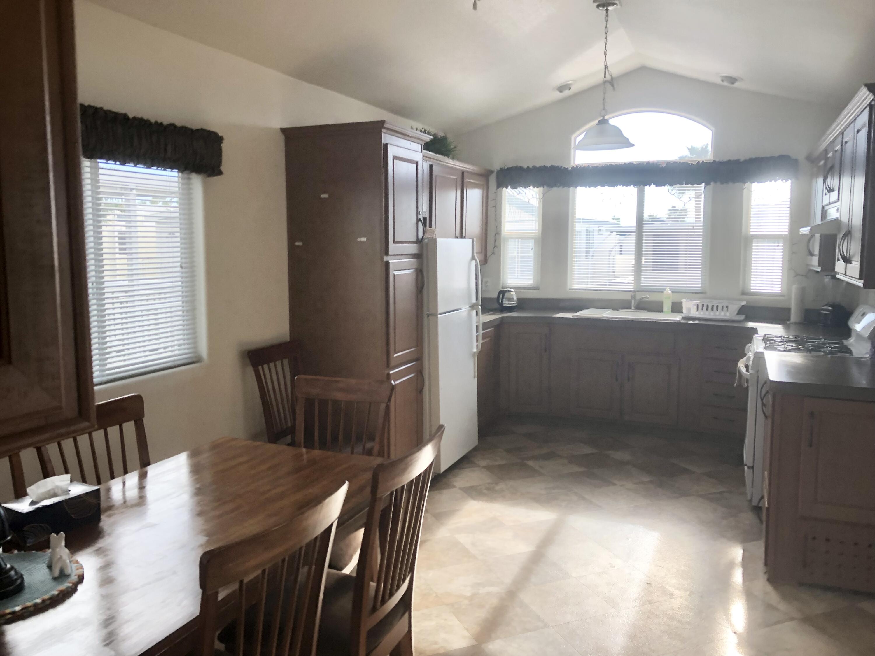 74711 Dillon Road Desert Hot Springs, CA 92241 - Photo 8 of 44 a kitchen with stainless steel appliances granite countertop a refrigerator a sink dishwasher a stove and a dining table with wooden floor