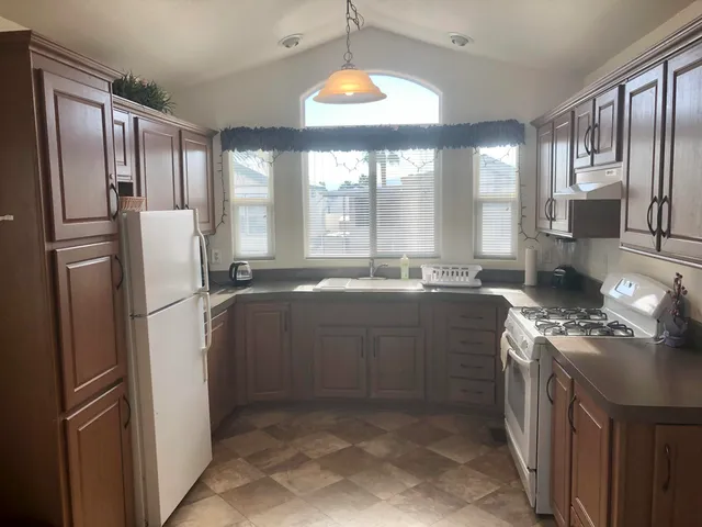 a kitchen with stainless steel appliances granite countertop a refrigerator a stove a sink and a large window