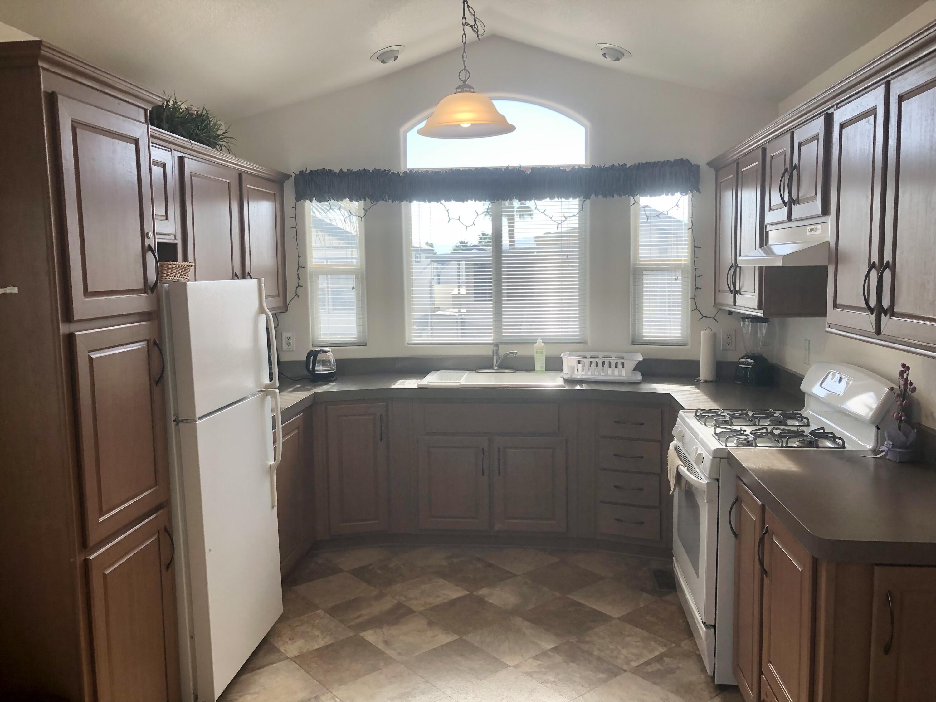 74711 Dillon Road Desert Hot Springs, CA 92241 - Photo 9 of 44 a kitchen with stainless steel appliances granite countertop a refrigerator a stove a sink and a large window