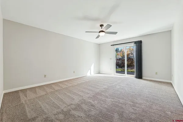 a view of an empty room with a ceiling fan and window