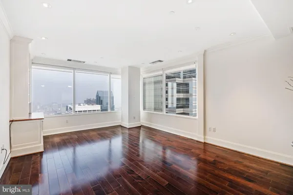 a view of an empty room with wooden floor and a window