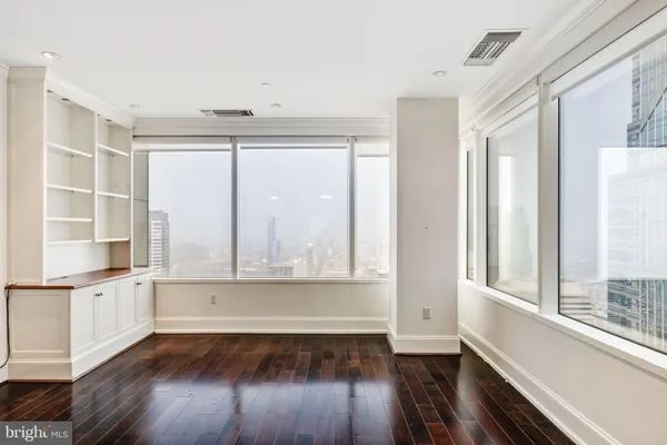 an empty room with wooden floor and windows