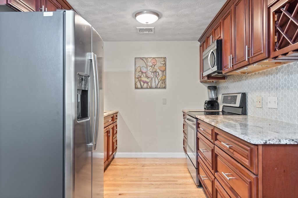 29 Karen Road Wakefield, MA 01880 - Photo 11 of 42 a hallway with granite countertop a sink and dishwasher a stove with wooden cabinets