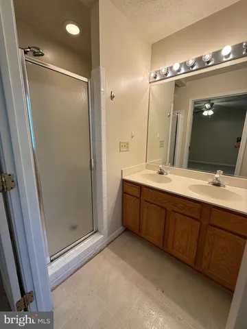 a spacious bathroom with a double vanity sink a large mirror and toilet