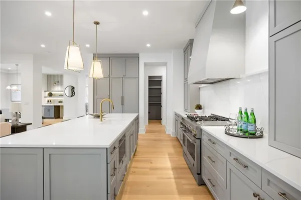 a kitchen with stainless steel appliances granite countertop a sink a stove a refrigerator and island with wooden floor