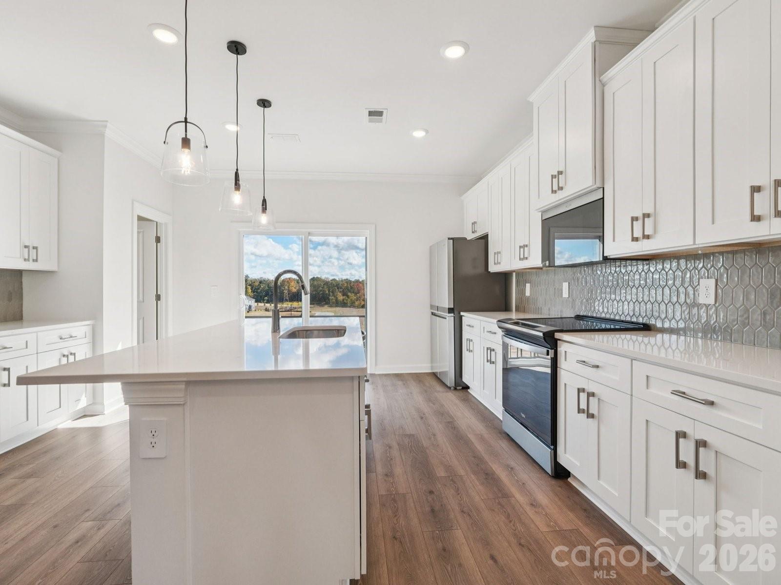 327 Golden Maple Court Fort Mill, SC 29708 - Photo 8 of 18 a large kitchen with granite countertop a stove a sink a refrigerator and white cabinets with wooden floor