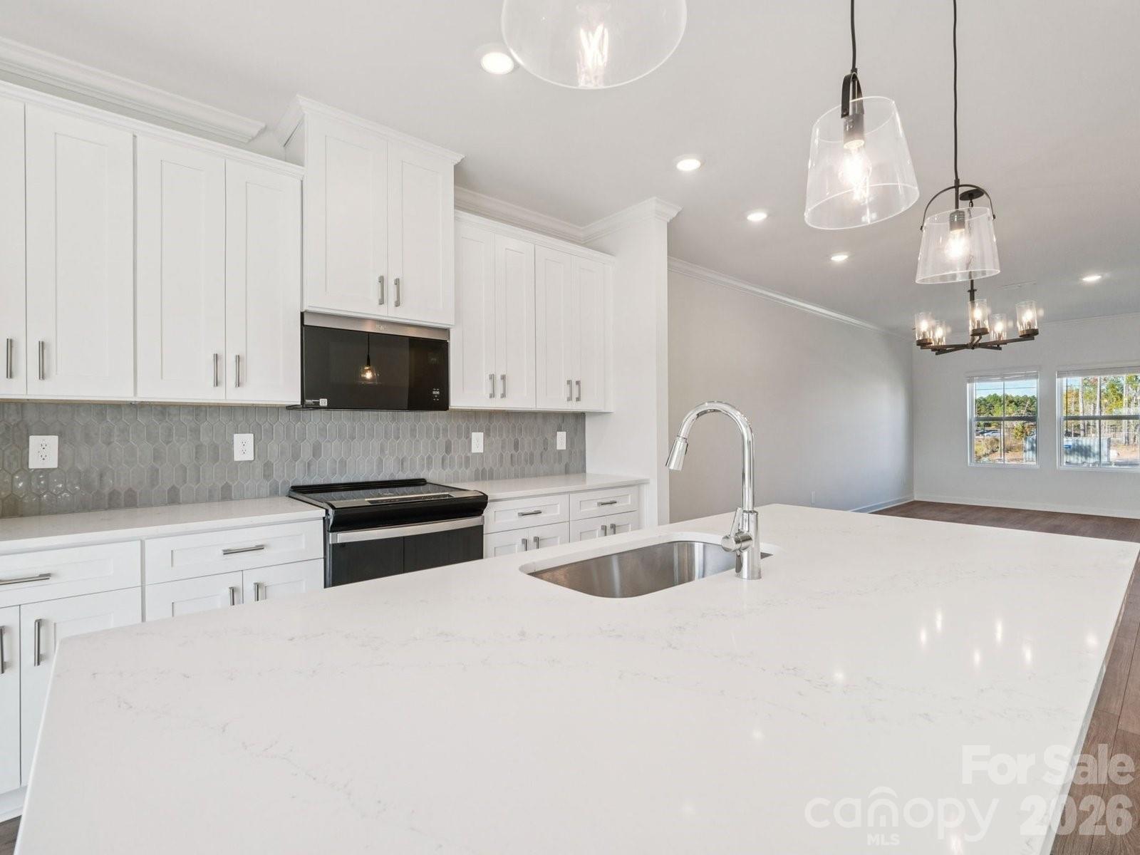 327 Golden Maple Court Fort Mill, SC 29708 - Photo 9 of 18 a large white kitchen with granite countertop a stove a sink a refrigerator and white cabinets with wooden floor