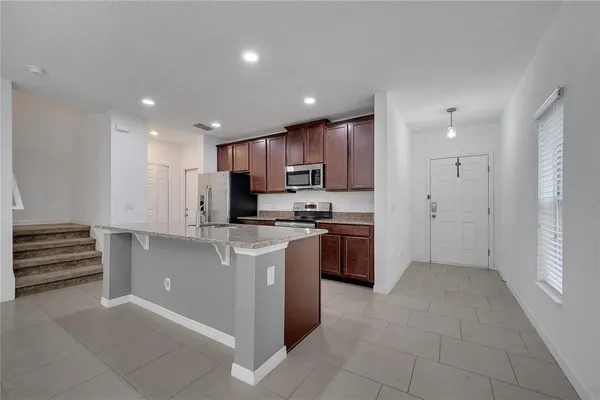 a view of kitchen with stainless steel appliances granite countertop a refrigerator and a sink
