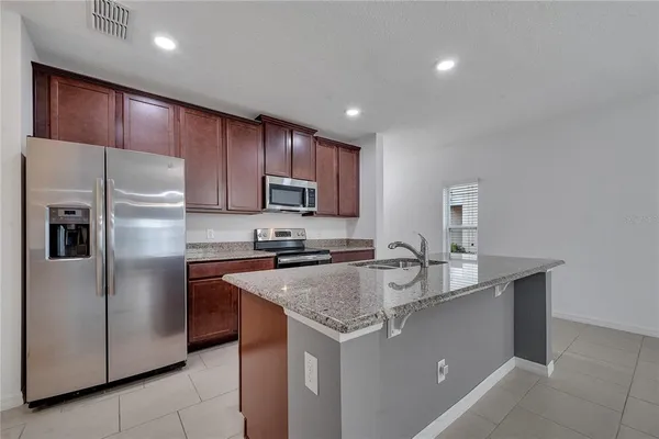 a kitchen with granite countertop kitchen island a sink stainless steel appliances and cabinets
