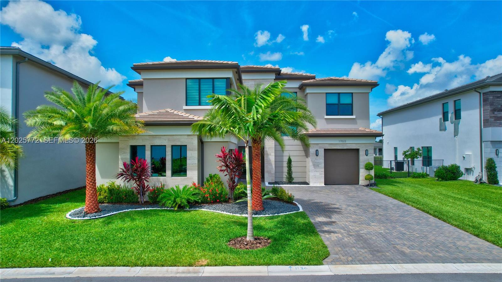 a front view of a house with a yard and palm trees