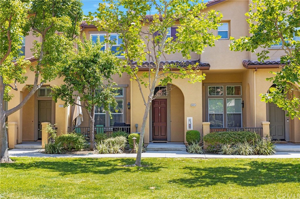 a front view of a house with a yard and a tree