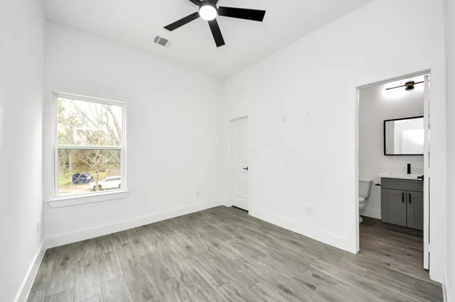 an empty room with wooden floor cabinet and windows