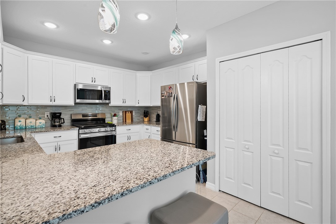 6187 Red Maple Manor Vero Beach, FL 32966 - Photo 5 of 31 a kitchen with stainless steel appliances granite countertop a refrigerator a stove and a sink with wooden floor