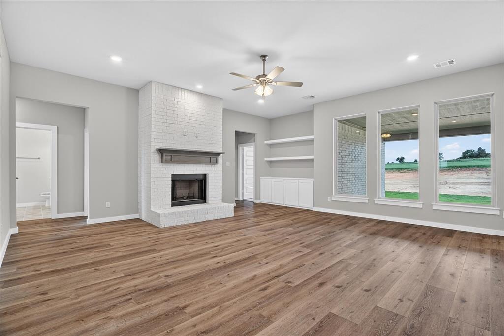 504 Clifton Court Springtown, TX 76082 - Photo 7 of 36 Spacious living area featuring wood-finish flooring, a white brick fireplace with a wood mantle, and recessed lighting