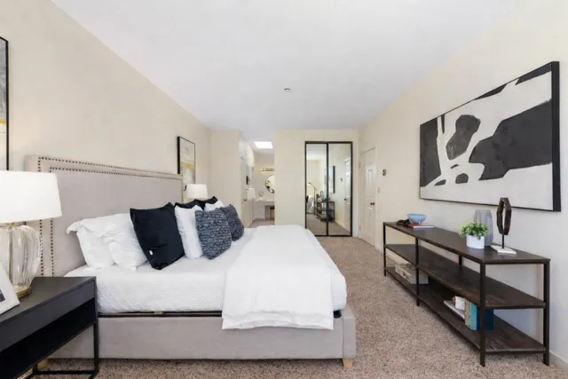 a bedroom with a bed a lamp and a large mirror on the dresser