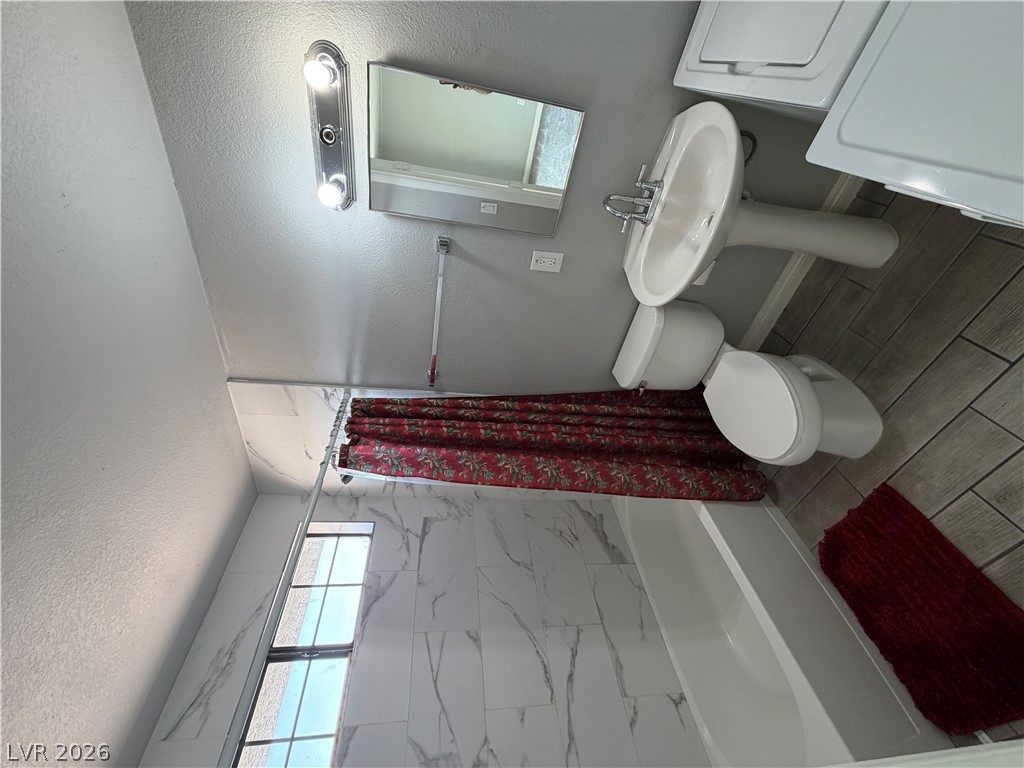 2820 South Sandhill Road, Unit A Las Vegas, NV 89121 - Photo 17 of 26 Tiled shower walls and a classic pedestal sink elevate this bathroom's appeal.