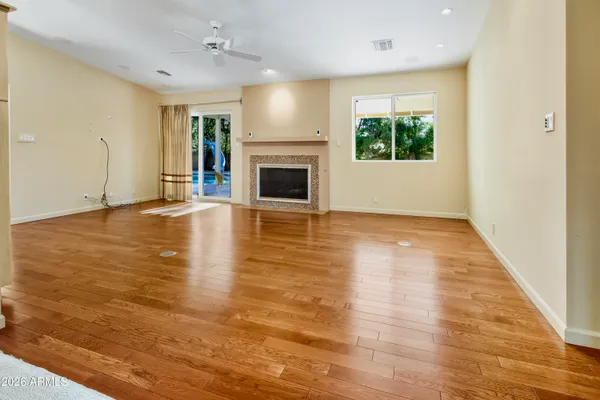 an empty room with wooden floor fireplace and windows