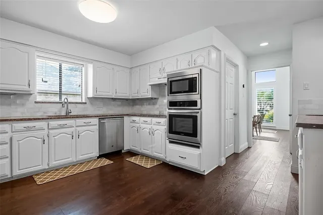 a kitchen with granite countertop white cabinets and stainless steel appliances