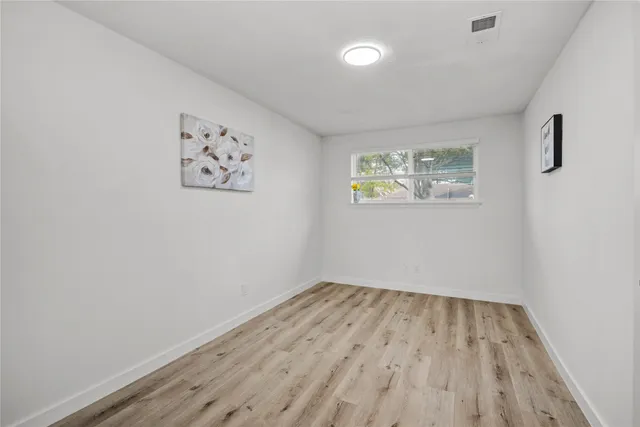 an empty room with a window and wooden floor