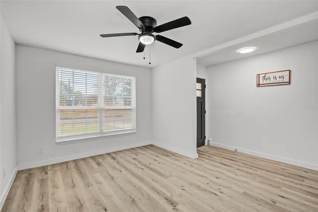 a view of an empty room with wooden floor and a window